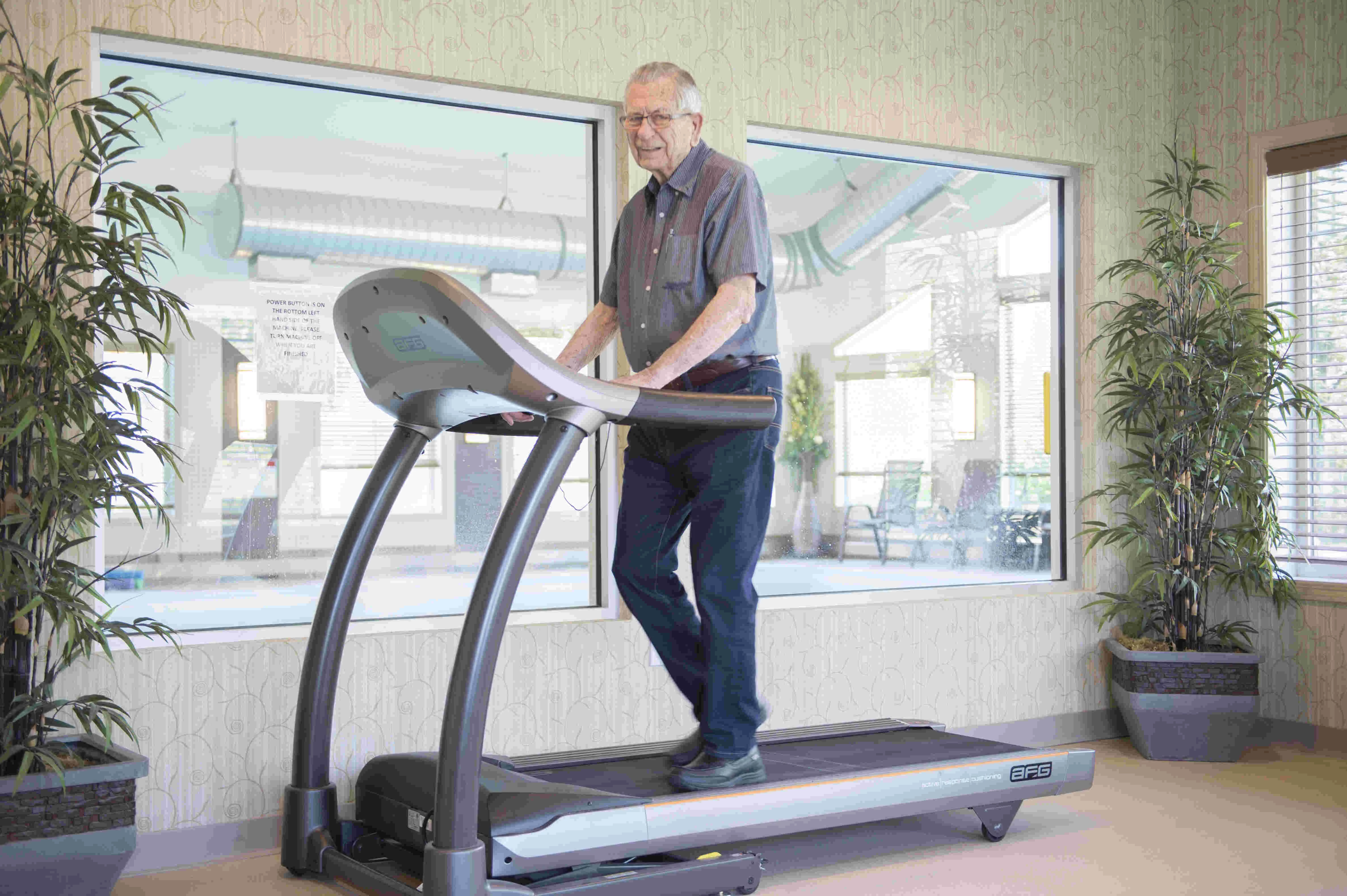 An elderly man walking on a treadmill and exercise programs for seniors