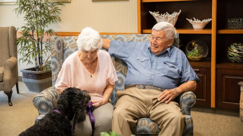 Two seniors sitting with their dog